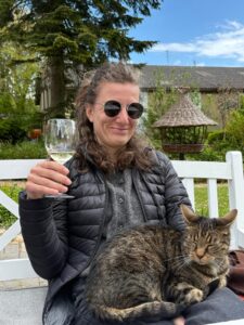 Aline mit Katze auf dem Schoß und Weinglas in der Hand